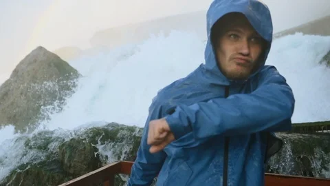 Man in blue raincoat under the waterfall dancing and have fun Stock Footage 87997503