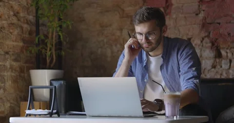 Man in blue shirt and glasses looks at his laptop and things. Decision making in Stock Footage