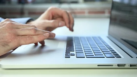 Man in a blue shirt in office presses keys on laptop Stock Footage 121971453