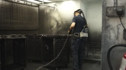 A man in a blue shirt is spraying a machine with a hose Stock Footage 302458073