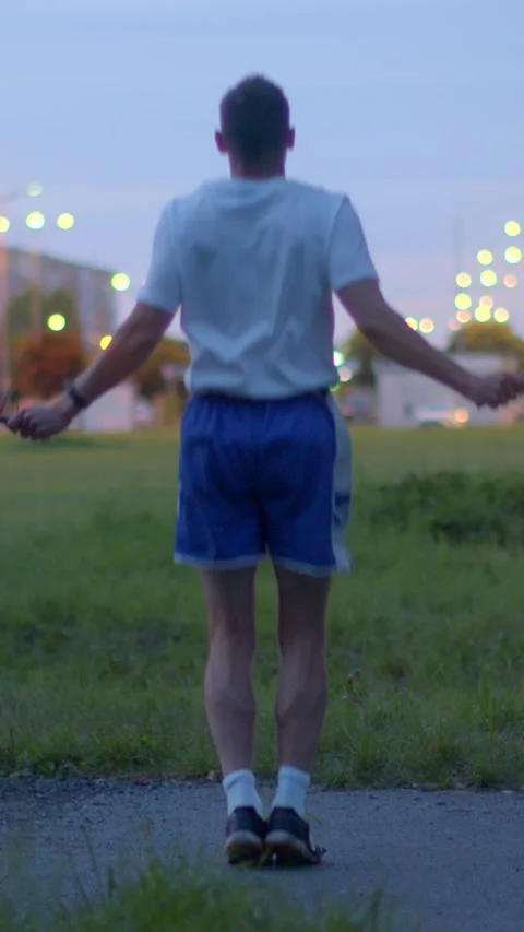 A man in blue shorts performs jump rope routines in a park Stock Footage 317339954
