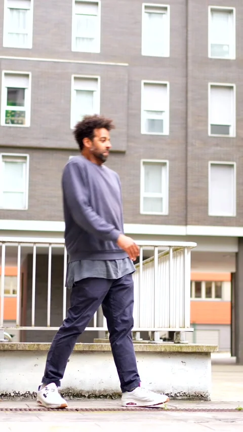A man in a blue sweatshirt and blue pants sits on a railing Stock Footage 277649800