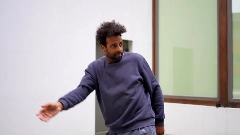 A man in a blue sweatshirt is standing in front of a white wall Stock Footage 277645627