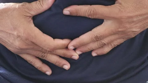 Man in blue T-shirtis using both hands to hold the abdomen due to severe pain Stock Footage 146303356