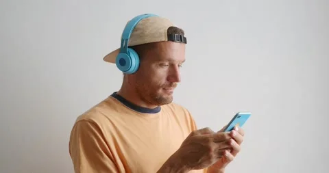 Man in blue wireless headphones using blue phone. Close-up. Stock Footage 156413941