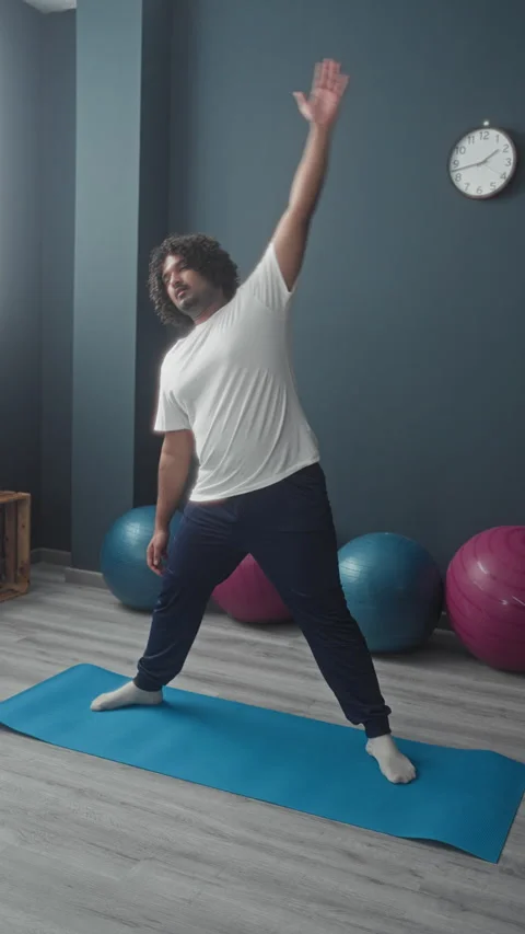 Man on blue yoga mat performing side stretch with arm raised and head tilte.. Stock Footage 337402238