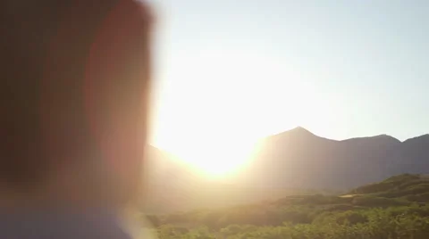 Man Blurry in Foreground, Looking Towards Hidden Sunset Over Mountain 動画素材 68723645