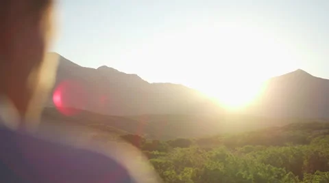 Man Blurry in Foreground, Looking Towards Sunset Over Mountain 動画素材 68723646