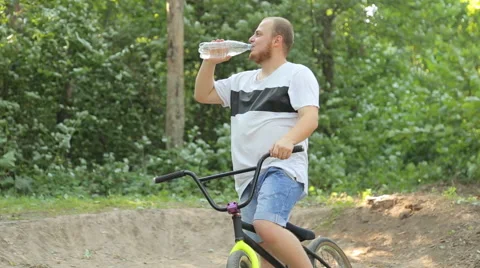 Man on bmx in the woods drinking clean water Stock Footage 65311043