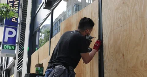 A man boards up a store after it was looted Stock Footage 131489885