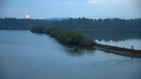 Man with boat rowing through the current on lake in sunset. Stockbeeldmateriaal 104607219