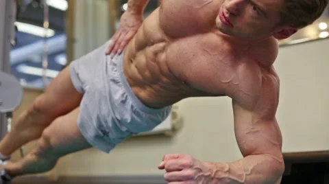 Man bodybuilder does exercise lying on one side, leaning at elbow Stock Footage