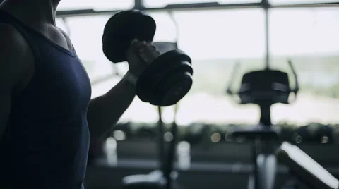 Man bodybuilder does exercises with dumbbells in gym Stock Footage