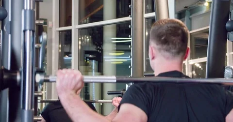 Man bodybuilder doing smith machine squat exercise with barbell at gym 4k video Stock Footage 71803455