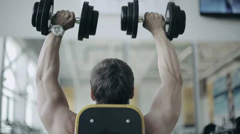 Man bodybuilder executes exercise with dumbbells in gym Stock Footage 52090769