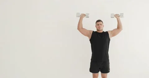 Man bodybuilder is lifting dumbbells up practicing hands and shoulders exercise. Stock Footage 143849031