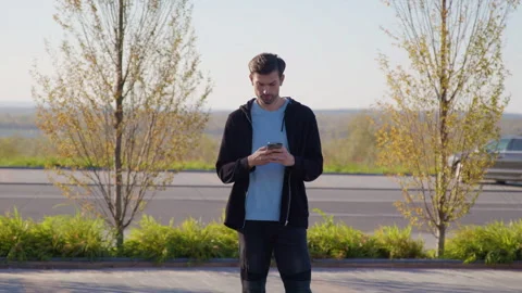 Man books car using car-sharing app on smartphone by road Stock Footage 300472872