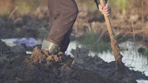 Man in boots digs with a shovel in the mud Vídeos de archivo 165139792