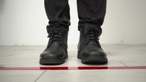 Man in boots standing behind the red tape floor marking for social distance 库存影片 147138558