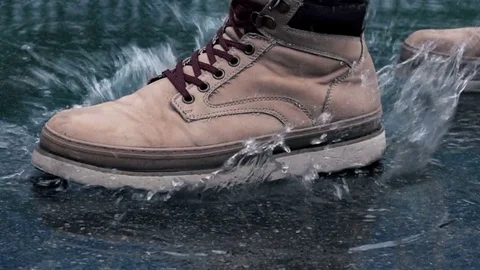Man in Boots Step on a Puddle and Create a Splash in Slow Motion Stock Footage 81584679