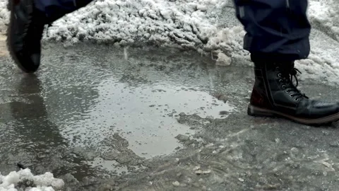 Man in boots stepping over and avoiding ice puddle with snow and slush NYC Stock Footage 148231017