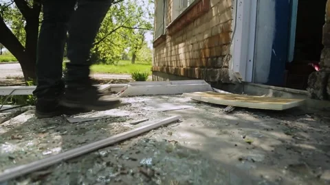 Man in boots steps over glass and debris after a rocket attack on a local school Stock Footage 329972761