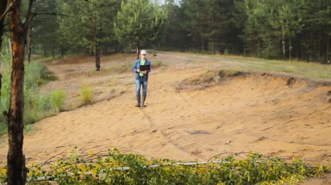 A man in boots walking on a sandy beach with laptop Stock Footage 64662368