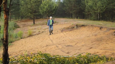 A man in boots walking on a sandy beach with phone Stock Footage 64663043