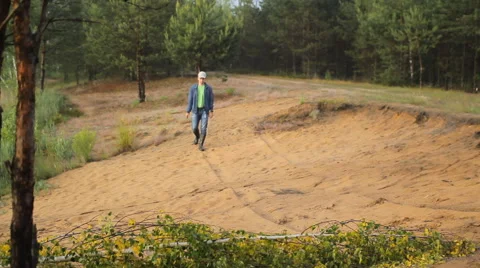 A man in boots walking on a sandy beach and touch smartwatches Stock Footage 64663189