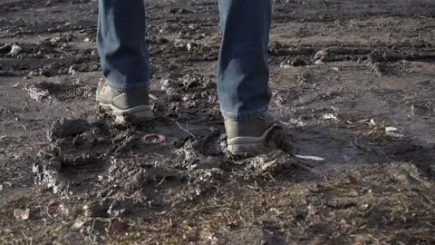 Man in Boots Walks Through the Mud, Splashing from a Puddle in Slowmo Stock Footage 169788888