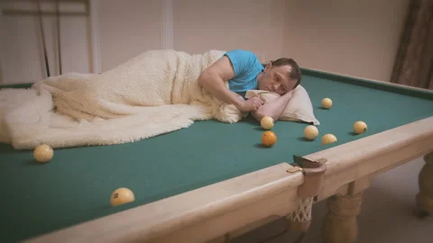 The man is bored, he lies on the pool table and rolls balls on the table Stock Footage 161127665