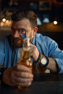 Man with bottle of beer sitting at counter in bar Stock Photos