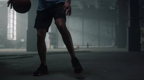 Man bouncing basketball ball between legs. Male player playing basketball Stock Photos
