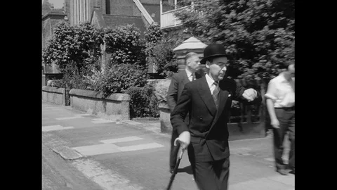 Man in bowler hat is rushing while another joins him on bike, UK 1959 Stock Footage 133384344