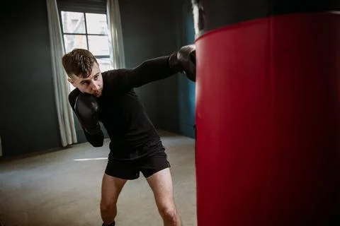 A man boxer beats a punching bag. Boxer practicing punches in the ring. The a Stock Photos
