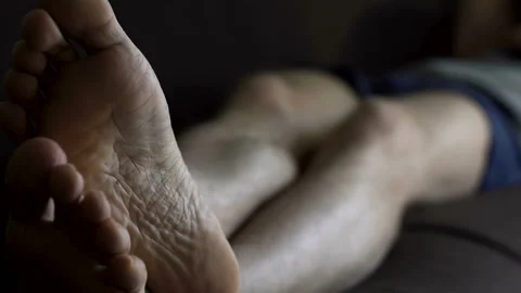Man in boxers sleeping on couch and scratching feet, skin problems and health Stock Footage 86781294