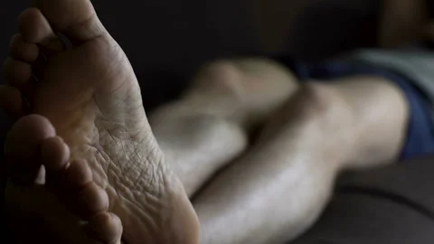 Man in boxers sleeping on couch and scratching feet, skin problems and health Stock Footage 86785820