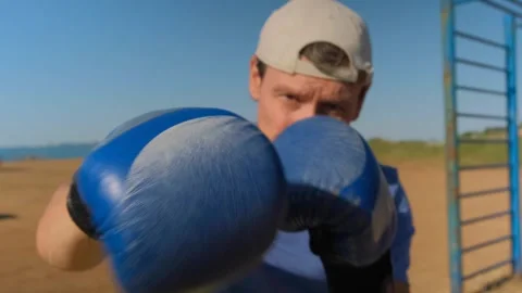 A man is boxing on the beach, throwing punches towards the camera Stock Footage 331455377