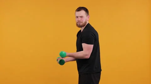 Man Boxing Playfully with Light Green Dumbbells on a Yellow Background Stock Footage 275921737