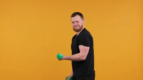 Man Boxing Playfully with Light Green Dumbbells on a Yellow Background Stock Footage 275922633