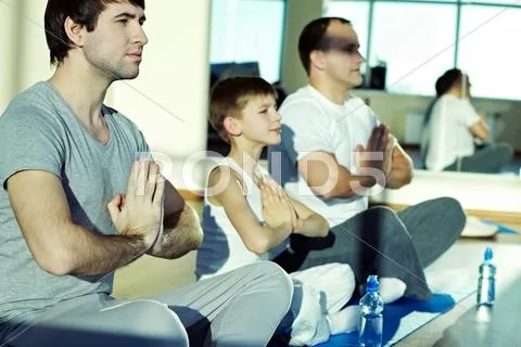 Man, boy and mature man sitting in a row in lotus position at gym Stock Photos