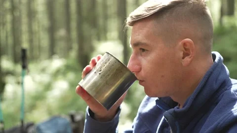 A man on a break while hiking drinks tea Close-up of cup of coffee in male hand Stock Footage 214324965