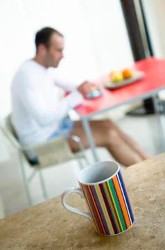 Man at breakfast table, cup in foreground Stock Photos