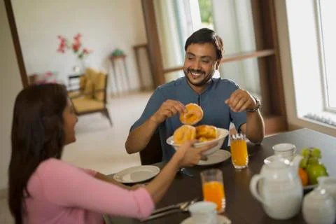 Man at breakfast table taking food from plate Stock Photos