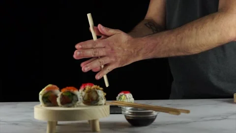 Man breaking chopsticks to take a roll from a plate full of sushi 動画素材 147013534