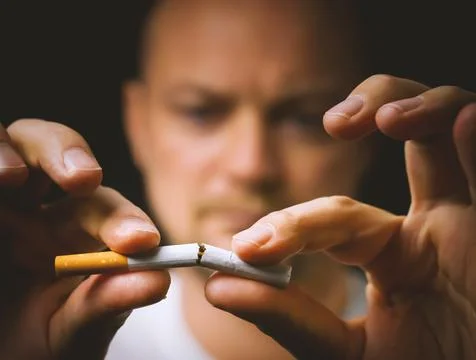 Man breaking a cigarette into two to quit smoking. Stock Photos