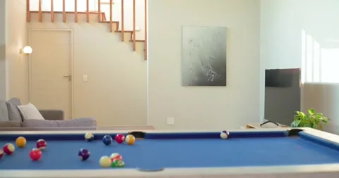 Man breaking rack, cue scattering balls, inspecting pool table for next shot at Stock Footage 335268931