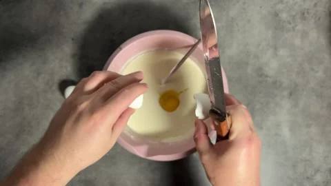 Man breaks 3 white chicken eggs with knife on gray kitchen table Stock Footage 297210196