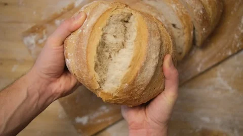A man breaks bread in the kitchen. Freshly baked fresh bread breaks on camera..  Stock Footage 148135870