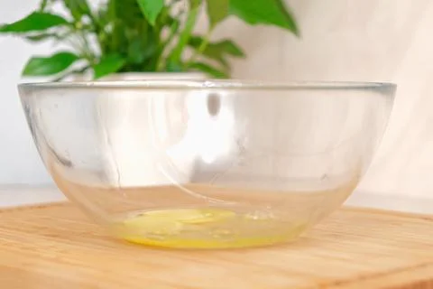 A man breaks a chicken egg on the edge of transparent glass bowl. The process of Foto stock